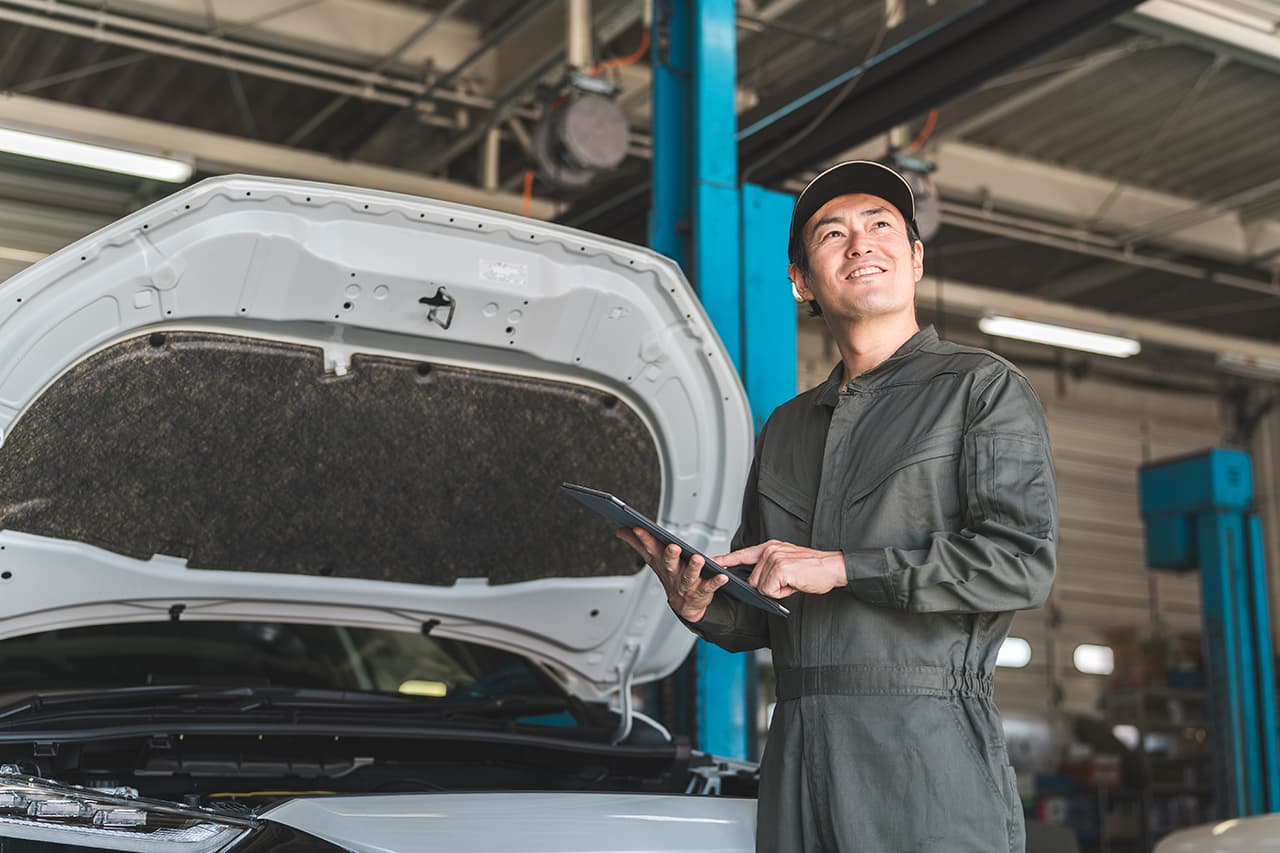 車のフロントを修理している整備士